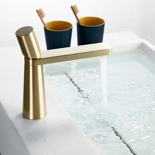 Angled view of LEONARD brushed gold basin faucet highlighting cylindrical spout and smooth lever arm