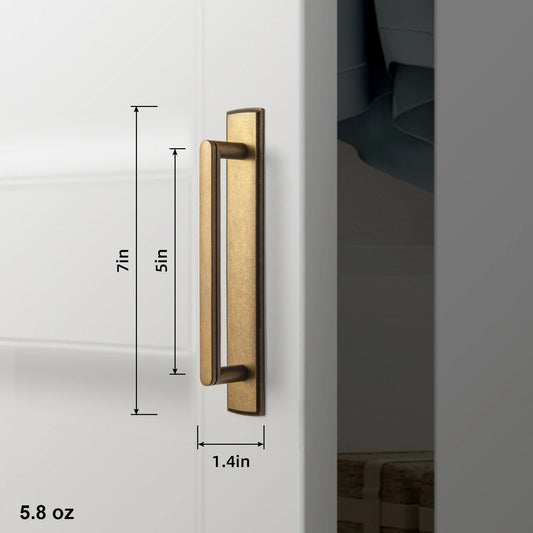 Angled view of LEWIS antique brass handle and backboard showing curved bar profile and decorative back plate