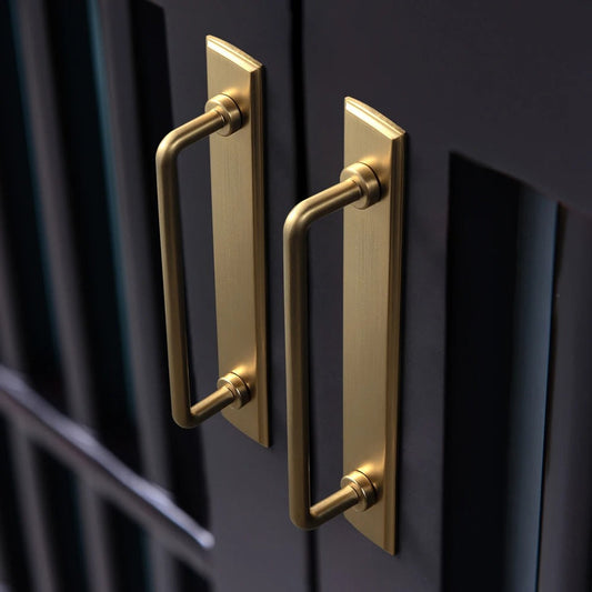 Angle view of TONI antique brass cabinet handle with backboard showing warm aged patina and bar handle profile