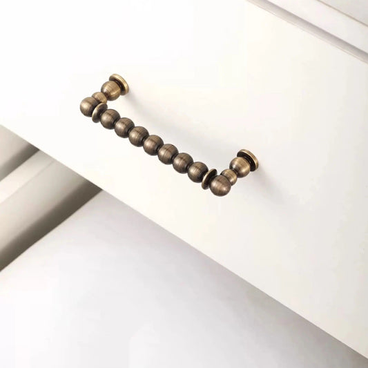 OLLIE brass round ball pull bar shot from a 45-degree angle highlighting the curved bar form