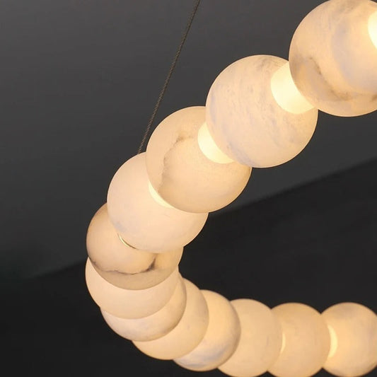 Cami di-pendant chandelier at side angle showing paired marble pendants and brass stem