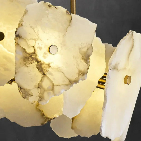 Lifestyle image of VALENTINO round marble chandelier glowing above a styled dining setting in an elegant home