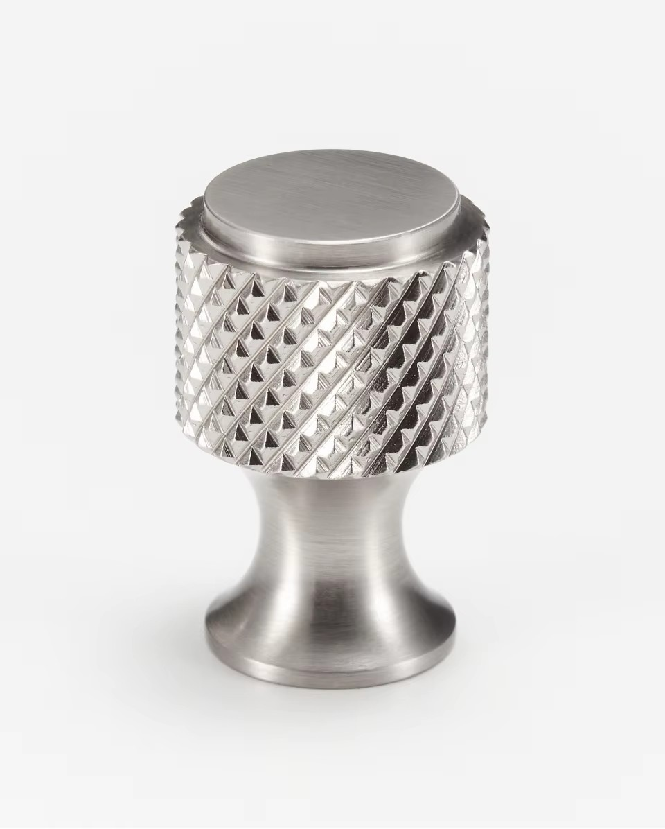 Knurled diamond-cut brass cabinet knob installed on kitchen cupboard door