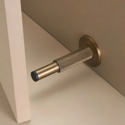 Knurled solid brass door stopper in antique brass — diamond-pattern grip, floor or wall mount