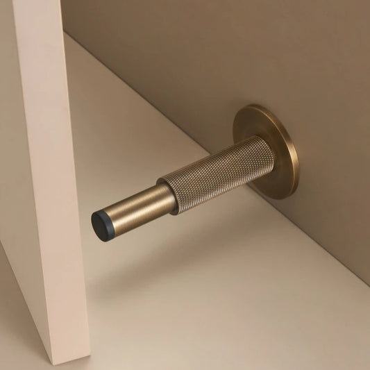 Knurled solid brass door stopper in antique brass — diamond-pattern grip, floor or wall mount