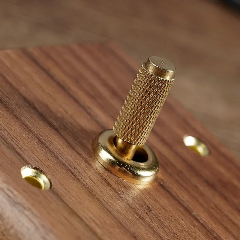 Walnut wood toggle switch close-up showing natural grain and precision-knurled brass lever