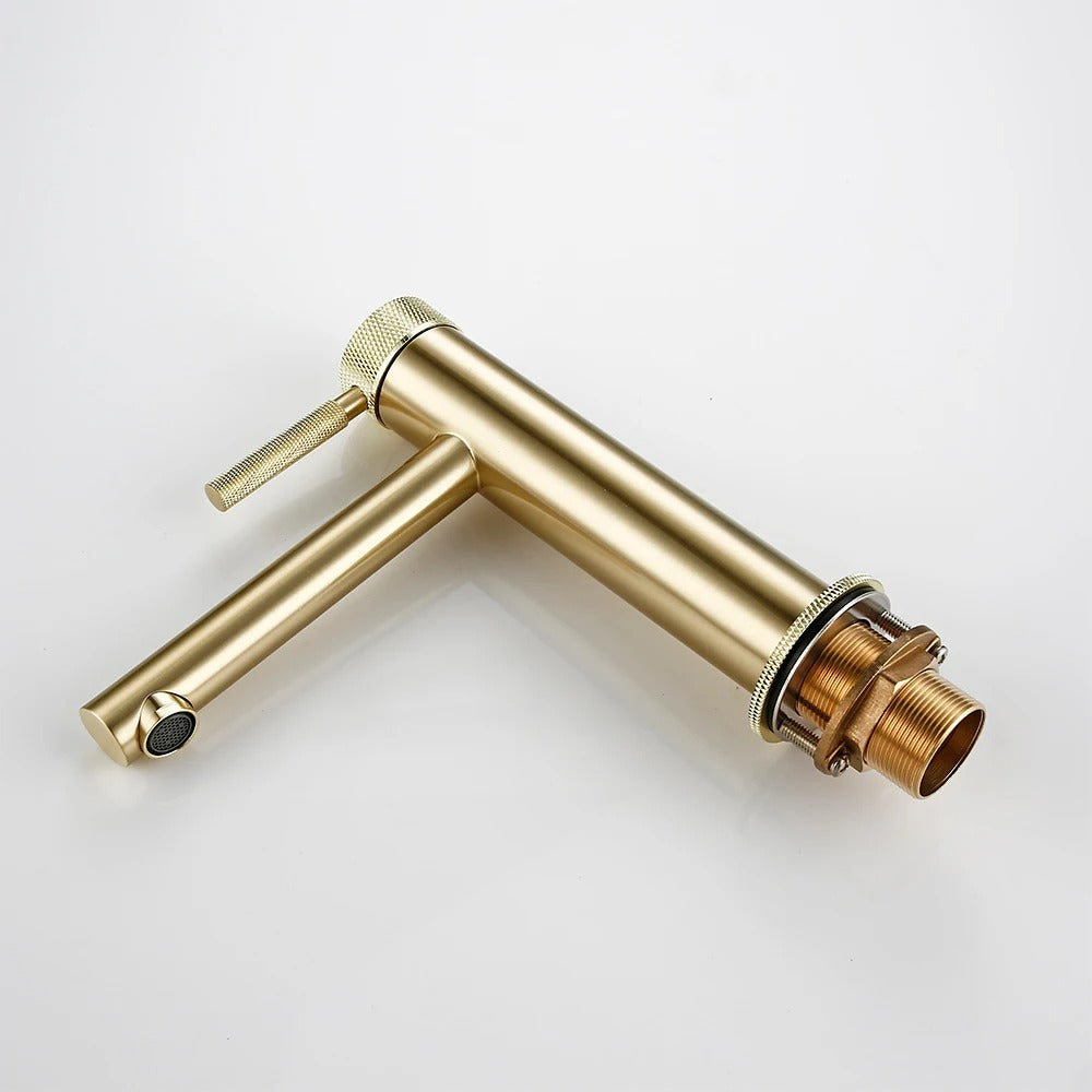 Rose gold knurled basin faucet in a luxurious bathroom setting with warm ambient lighting