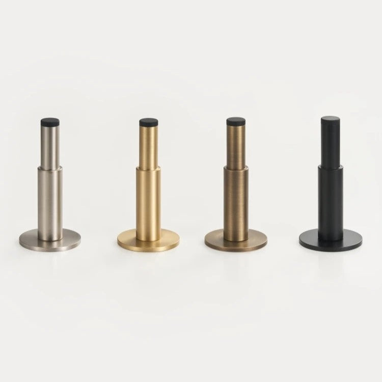 Plain solid brass door stopper styled in modern bathroom with warm antique brass hardware